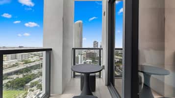 Ein Balkon mit Tisch und Stühlen, der einen Blick auf die Stadt und ein hohes Gebäude bietet.
