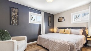 Ein Schlafzimmer mit einem großen Bett, einem Sessel und Bildern an den Wänden.