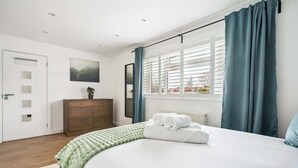A bedroom with a bed, a dresser, a window with curtains, and a door. - Contemporary 3-Bed House - Parking - By Tempstay (Windsor)