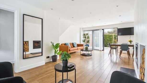 A spacious living area with a large mirror, a sofa, a coffee table, and a dining area with a table and chairs. - Contemporary 3-Bed House - Parking - By Tempstay (Windsor)