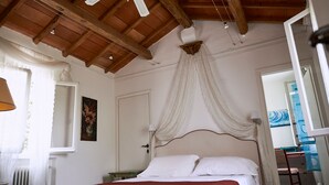 Een slaapkamer met een houten plafond, een bed met witte lakens, een nachtkastje en een schilderij aan de muur.