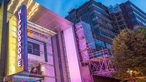 Un edificio moderno con un llamativo letrero que dice 'Hippodrome', indicando un teatro o recinto de entretenimiento.