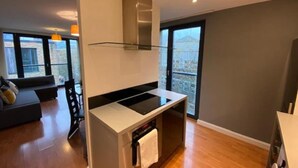 Una cocina moderna con estufa integrada, protector de vidrio y vistas a la ciudad a través de amplios ventanales.