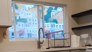 Una cocina con ventana, armarios y un lavamanos.