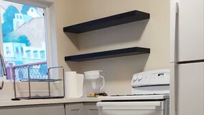Una cocina con armarios de colores claros, un horno blanco y un refrigerador.