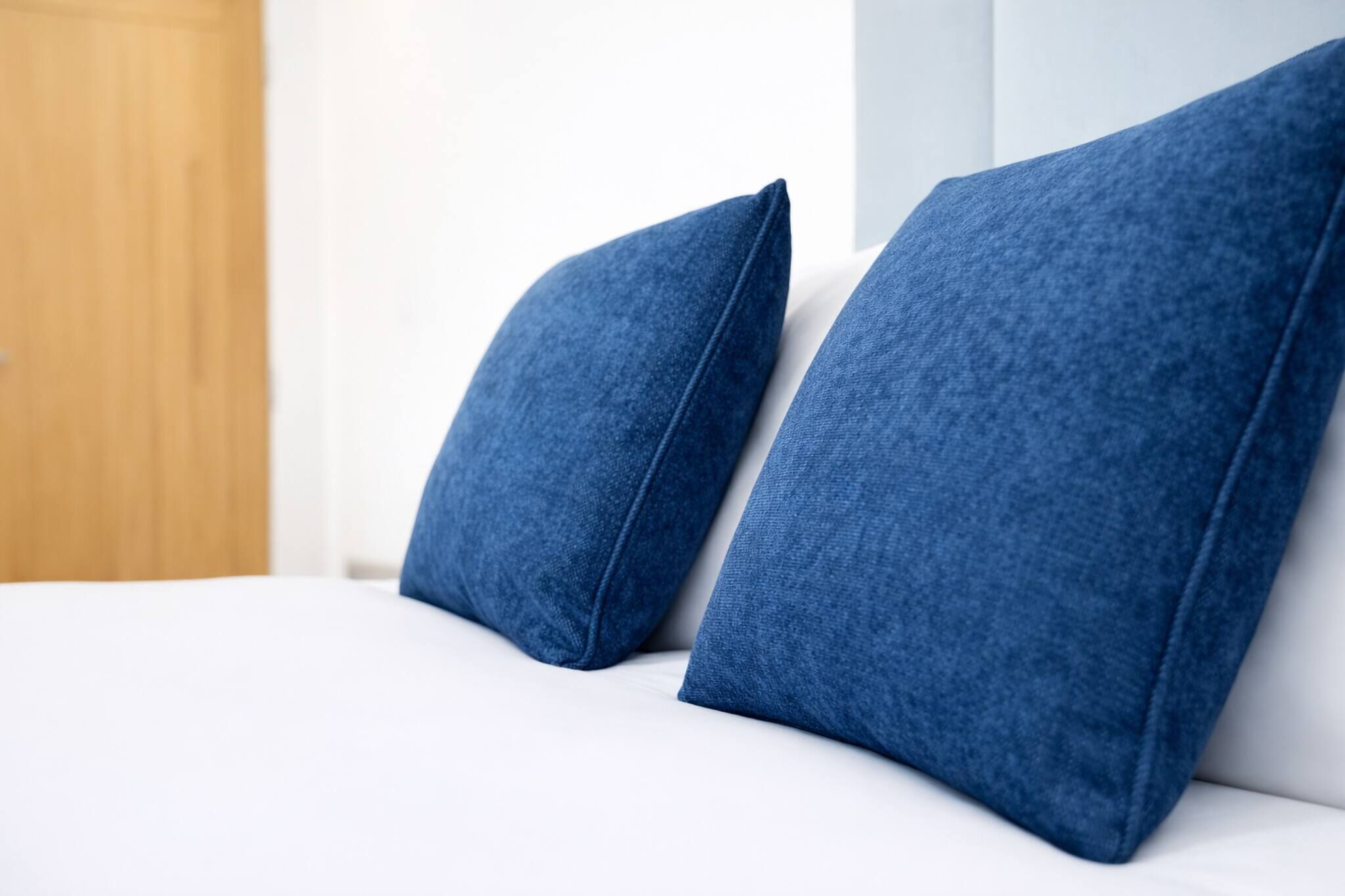 A bed with two blue pillows and a white mattress.