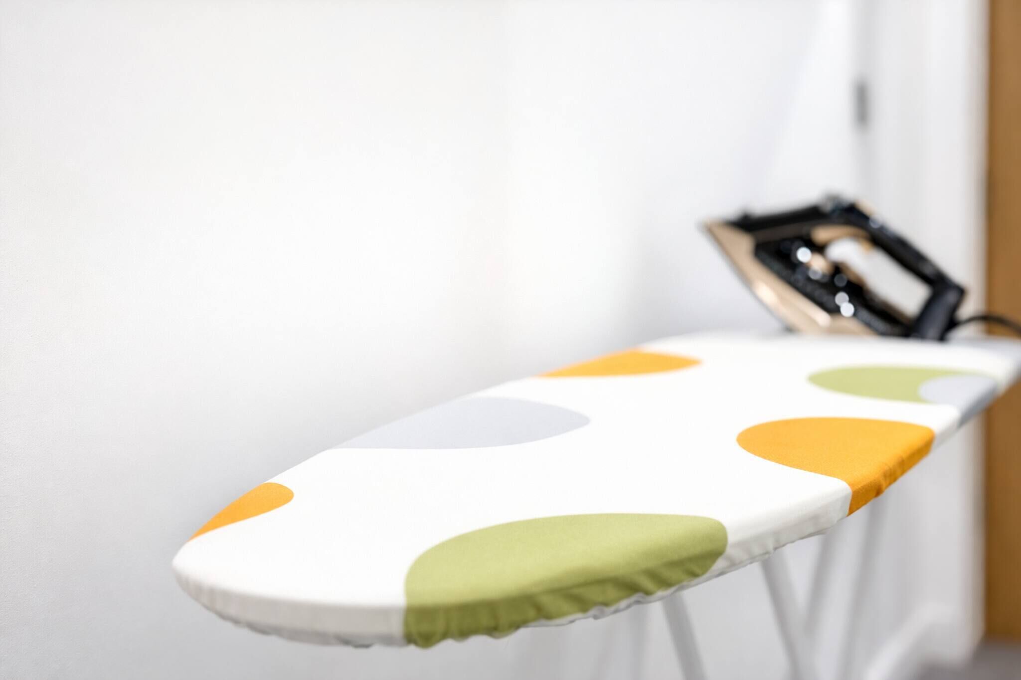 Una tabla de planchar con superficie blanca y lunares de colores.