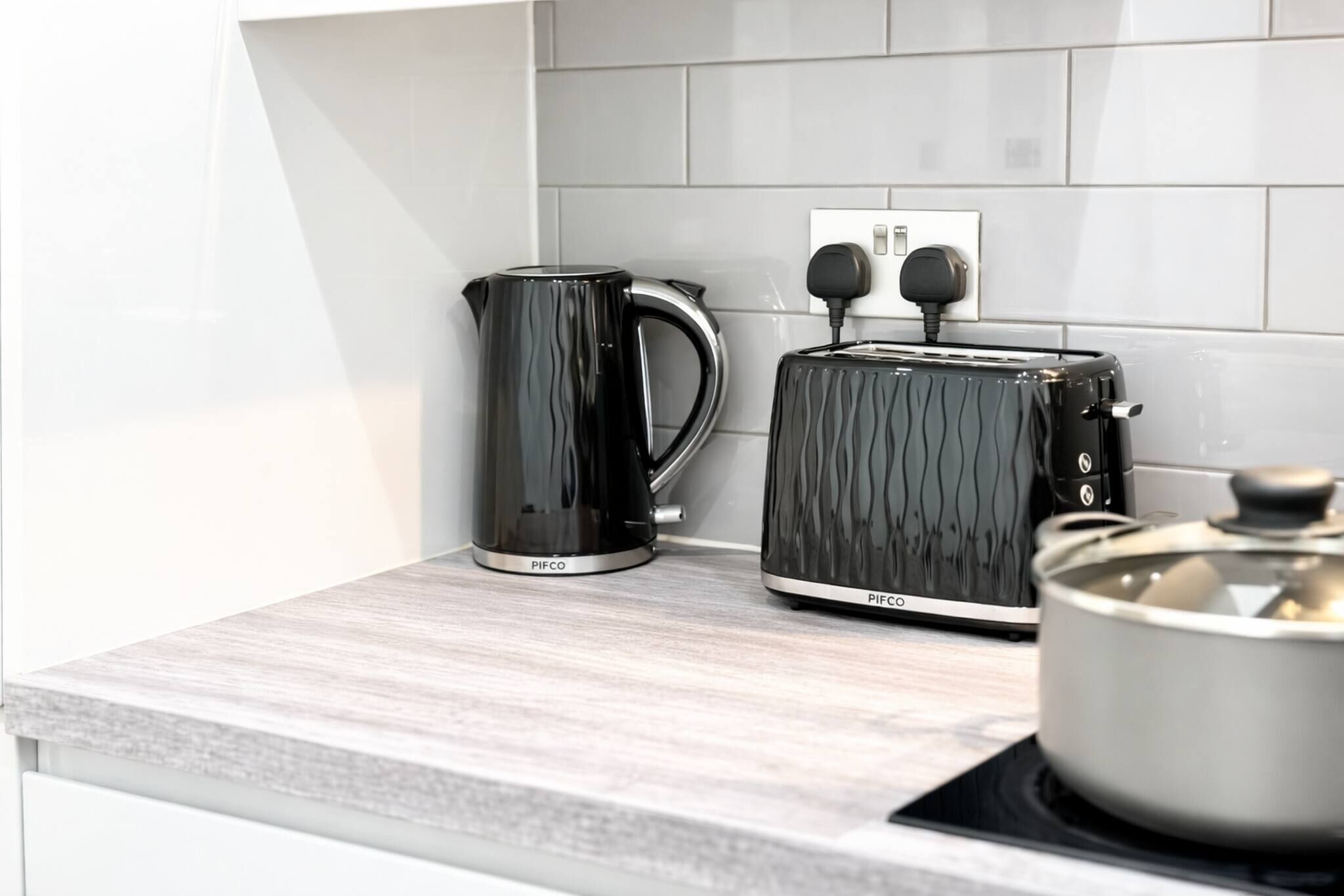 A kitchen with a black coffee maker, a toaster, and a pot on the counter.