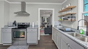 Une cuisine moderne dotée d’un four encastré, d’une hotte en acier inoxydable et de plans de travail en granit.