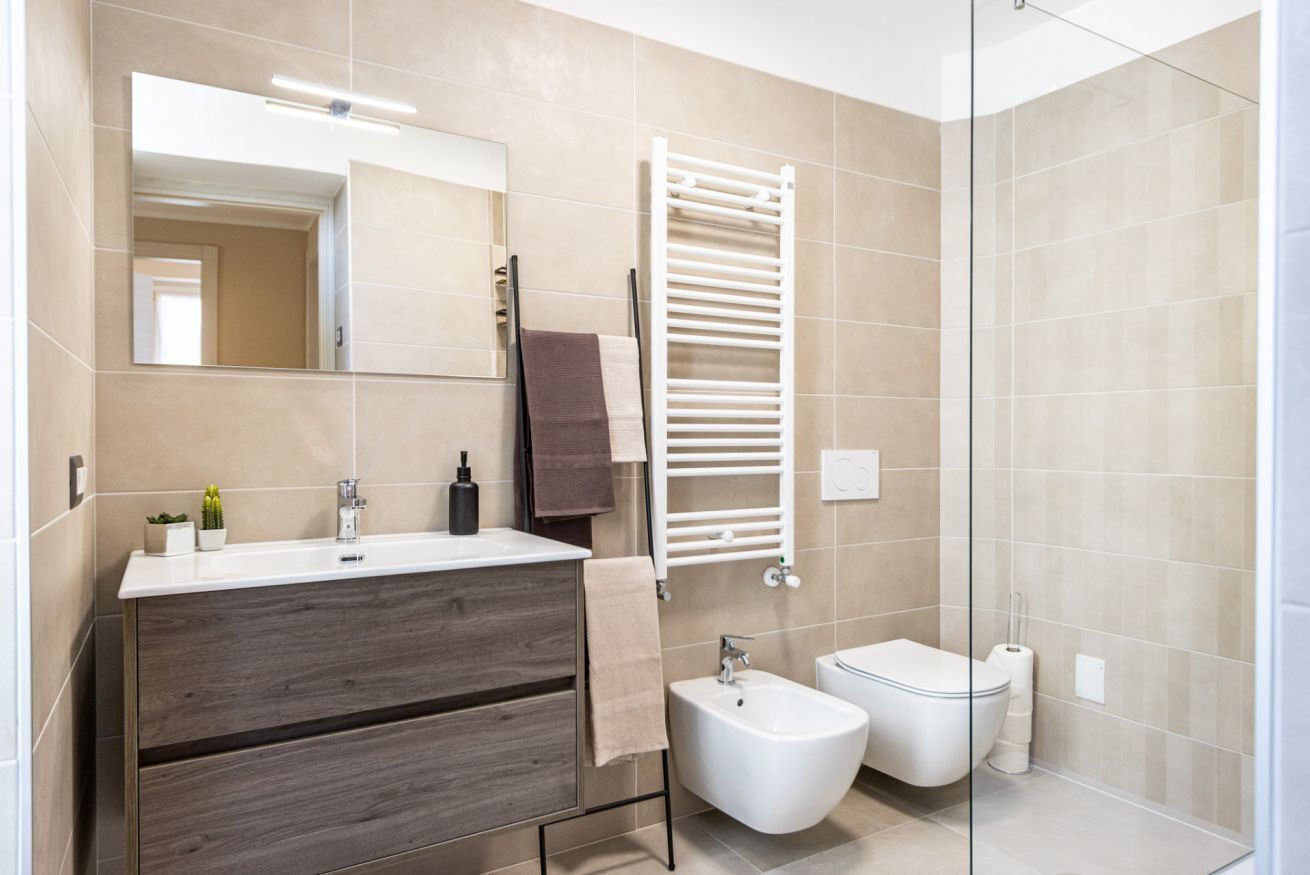 Ein modernes Badezimmer mit Waschtisch, Bidet, Toilette und einer Duschkabine aus Glas.