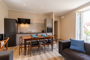 A compact living space with a kitchenette, dining area, and a sofa with a view. - Le Dalie - Beautiful Apartment Stresa - Magognino (Magognino)