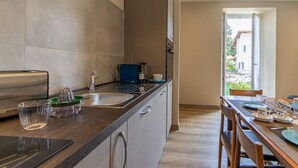 A modern kitchen with a built-in toaster, a sink, and a dining area with a table set for two. - Le Dalie - Beautiful Apartment in Stresa - Magognino - By Guestaly (Magognino)