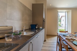 Une cuisine moderne équipée d’un grille-pain encastré, d’un évier et d’un coin repas avec une table dressée pour deux personnes.