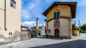 A street with buildings, including a church with a bell tower, and a building with a large arched window. - Le Dalie - Beautiful Apartment in Stresa - Magognino - By Guestaly (Magognino)