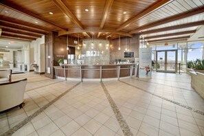 A spacious lobby with a reception desk, tiled flooring, and a high ceiling with wooden beams. - Luxury Beachfront 3 Bedroom @ Aqua Resort, Walk to Pier Park and Topgolf & More! (Panama City Beach)