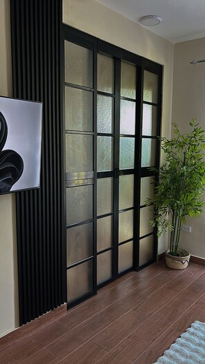 A room with a sliding glass door, a potted plant, and a wall-mounted light fixture. - Romantic and tropical apartment in the charming city of Puerto Plata (Puerto Plata)