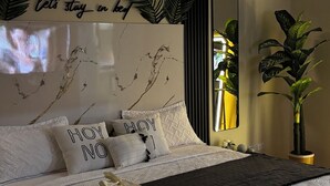 Ein ordentlich bezogenes Bett mit einer weißen Decke und zwei Kissen, eines mit dem Aufdruck 'HOY NO'.