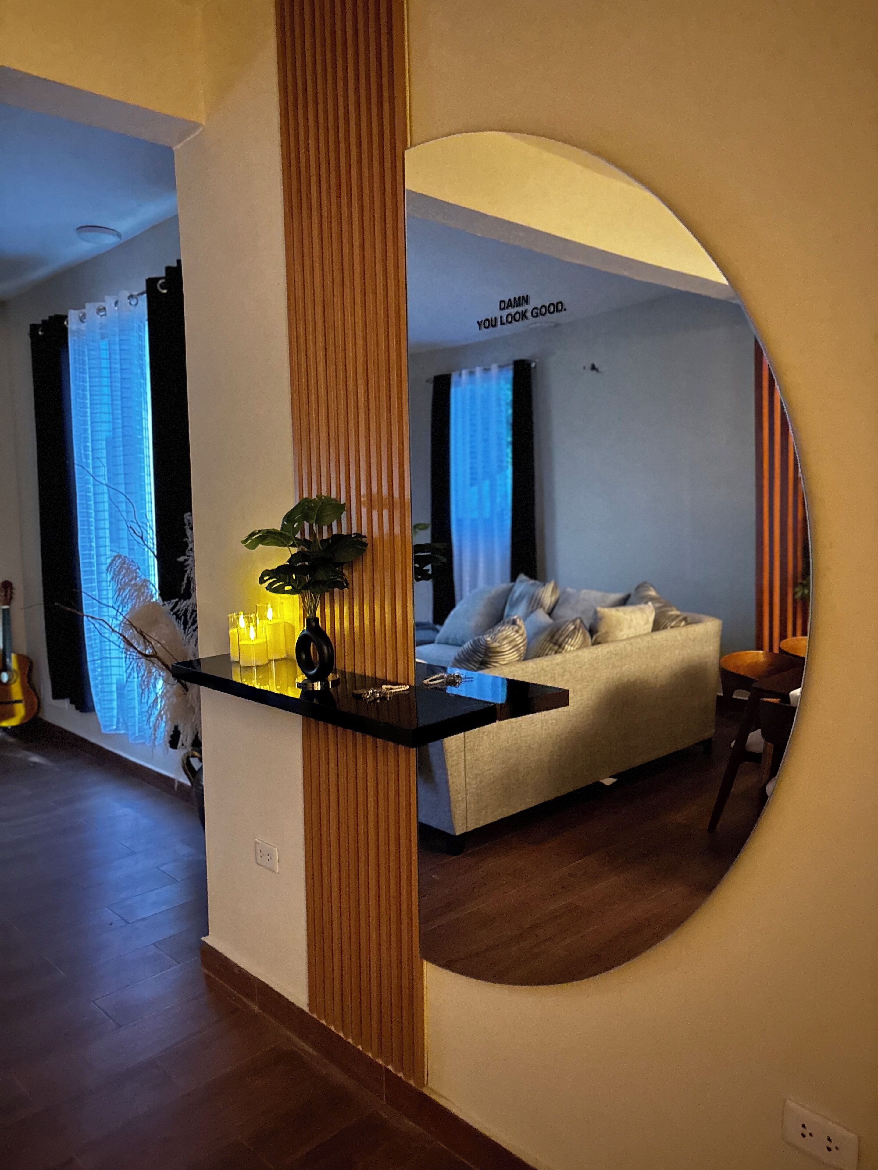 Una sala de estar moderna con un sofá, una mesa de centro y un espejo que refleja la habitación.
