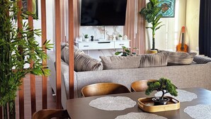 Ein modernes Wohnzimmer mit einer Couch, einem Fernseher und Zimmerpflanzen.