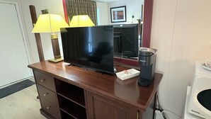 A wooden entertainment center with a flat-screen TV, two lamps, a coffee maker, and a mirror. - Seeleys Bay Motel and Resort (Seeleys Bay)