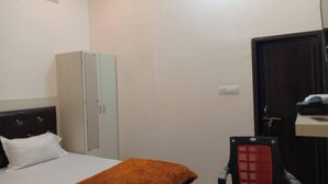 A hotel room with a bed, a wardrobe, a desk, and a chair. - Hotel Silsila (Varanasi)