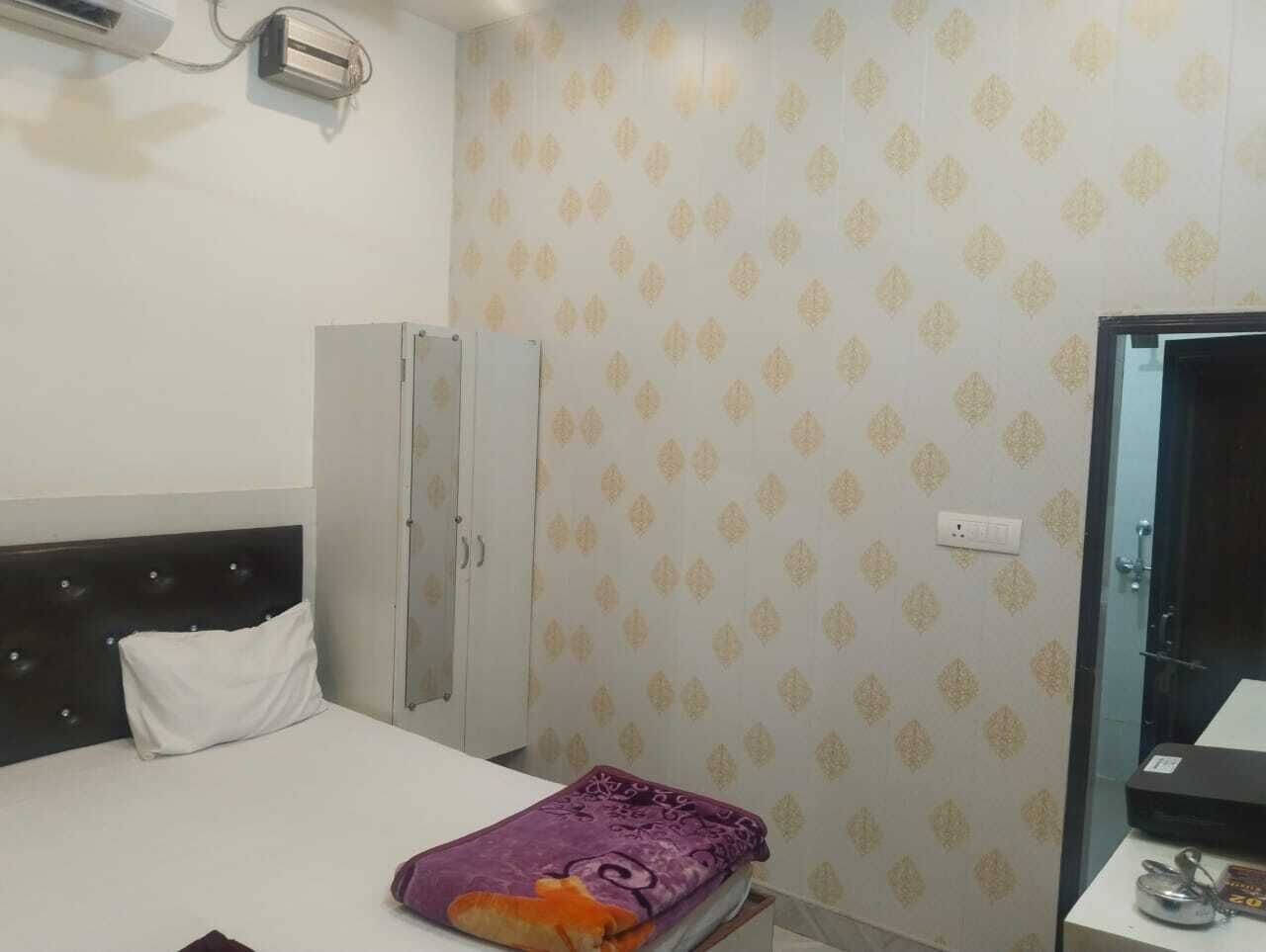 Ein Hotelzimmer mit Bett, Kleiderschrank und Schreibtisch mit Computer.