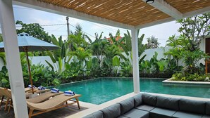 Ein Poolbereich mit überdachter Sitzgelegenheit, Liegestühlen und Pool.