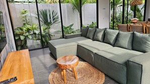 Ein modernes Wohnzimmer mit einem Ecksofa, einem Couchtisch aus Holz und einem gewebten Teppich.
