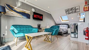 Una sala de estar moderna con un sofá color turquesa, una mesa de centro y un televisor mostrando 'NETFLIX'.