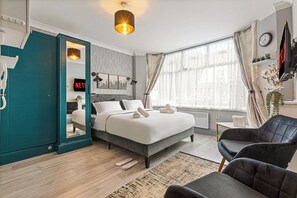 A modern bedroom with a bed, a chair, a desk, and a window. - Imperial Inn Apartments (London)
