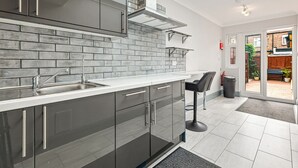 Una cocina moderna con armarios grises, un lavamanos de acero inoxidable y un revoque de azulejos.