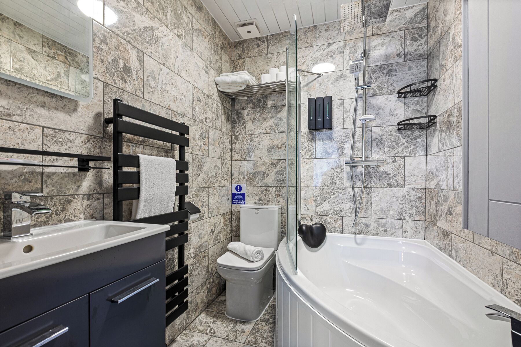 A modern bathroom with a bathtub, toilet, and shower area.