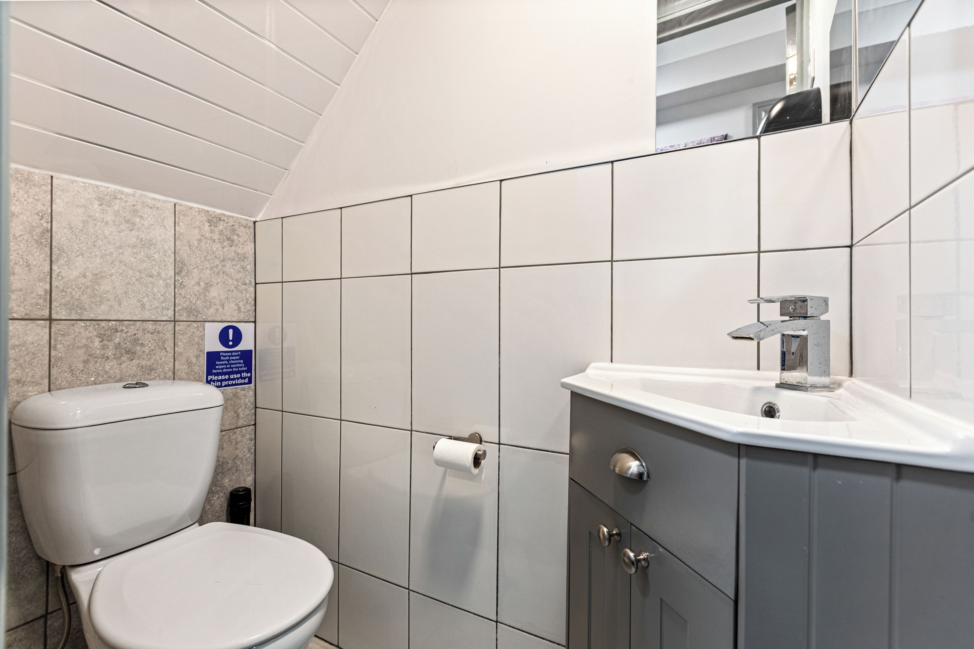 A bathroom with a toilet, sink, and tiled walls.