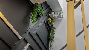 Un interior moderno con una escalera, paredes blanco y negro, y plantas verdes en las paredes.
