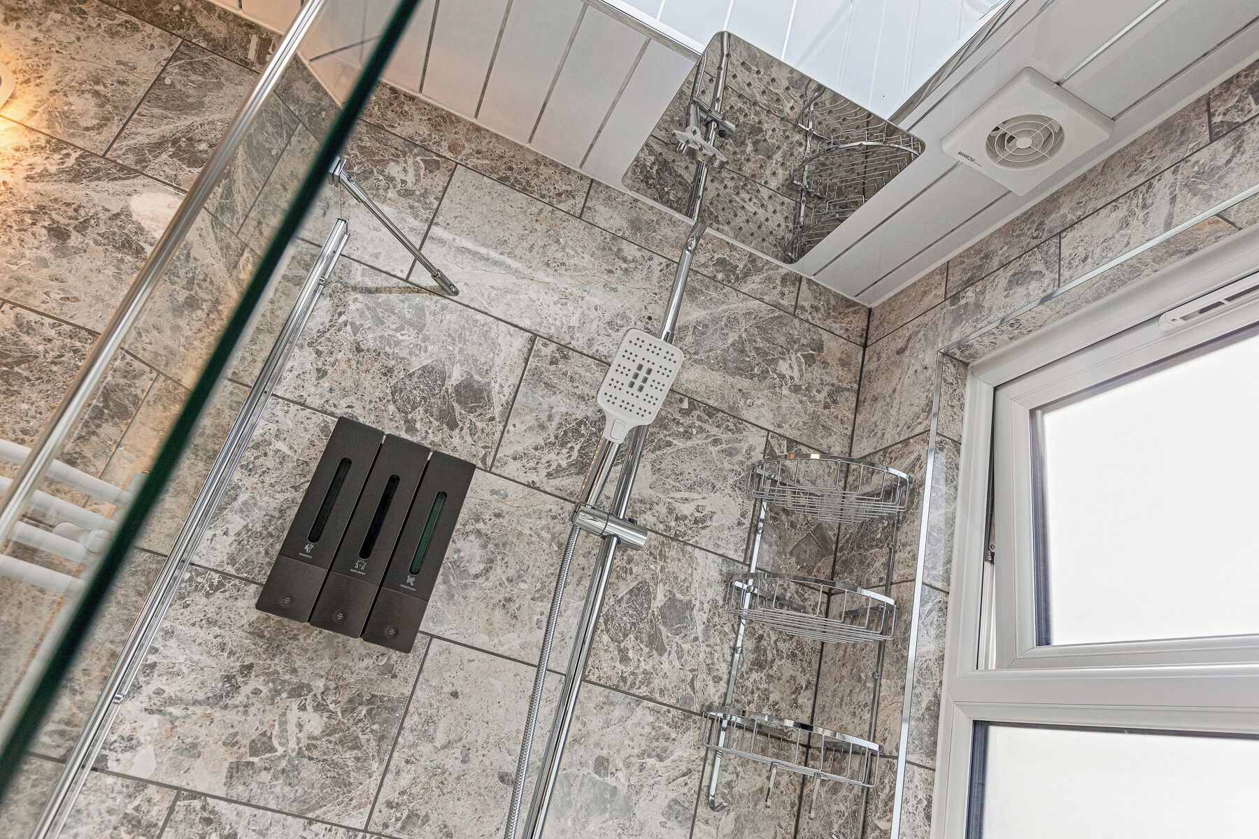 Ein modernes Badezimmer mit Dusche, Lüftungssystem und Glastür.