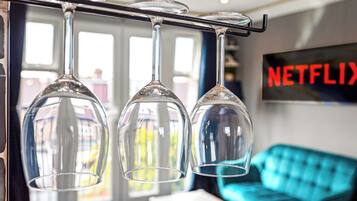 Three wine glasses hanging from a bar, a blue sofa, and a wall-mounted sign with the word "NETFLIX".