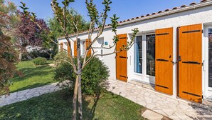 A building with a white exterior, wooden shutters, and a stone pathway leading to the entrance.