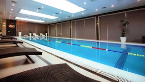 A long indoor swimming pool with clear lane dividers, lounge chairs, and ceiling lights. - Rauza Hotel Tashkent (Tashkent)
