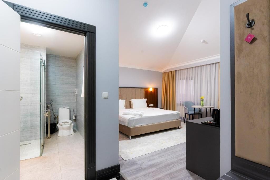 Een moderne hotelkamer met een bed, een bureau en een badkamer.