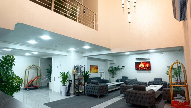 A spacious lobby with a high ceiling, multiple seating areas, and a central fire feature. - Rauza Hotel Tashkent (Tashkent)
