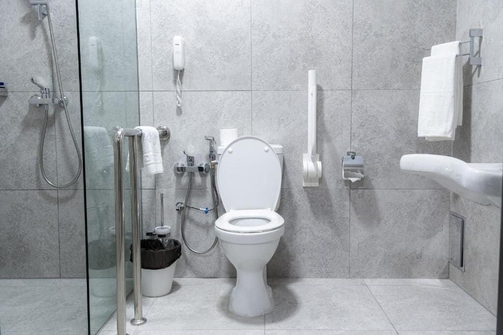 A modern bathroom with a glass-enclosed shower, a toilet, and a bidet.