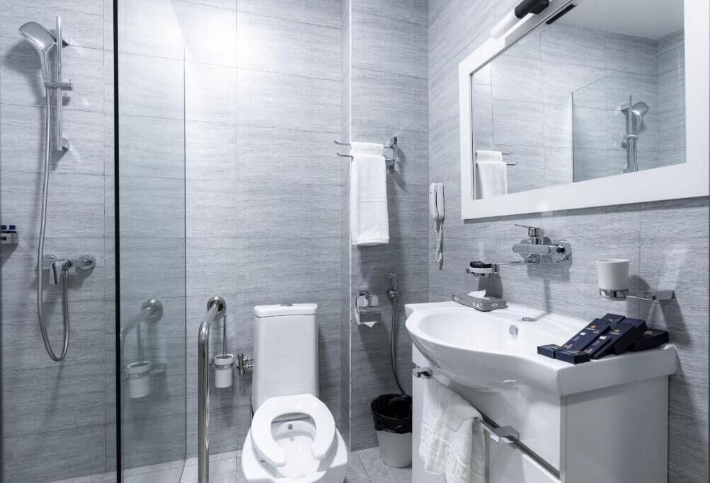 A modern bathroom with a glass shower enclosure, a toilet, a sink with a mirror, and a towel rack.