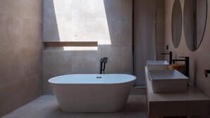 Un baño moderno con una bañera independiente, un lavabo y un espejo.