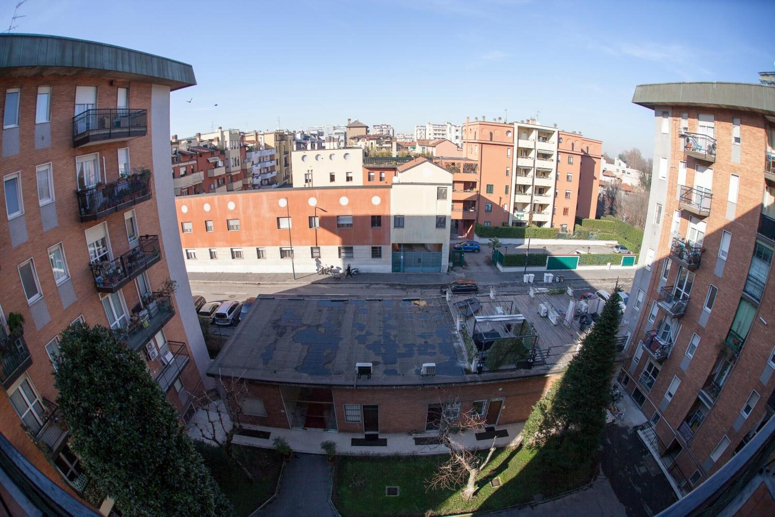 Un immeuble de grande hauteur doté de nombreux balcons, d’un espace de stationnement et d’un petit espace vert.