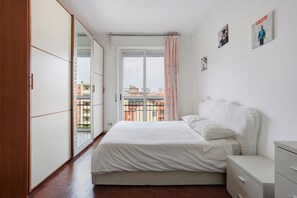 A bedroom with a bed, a wardrobe, a dresser, and a window with a view of buildings. - Bright Four-Room Apartment in Milan Affori with Balcony in Every Room (Milan)