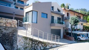 A modern two-story building with a stone retaining wall, a balcony, and a car parked in front. - Sea View Frini- Lefkada (Lefkada)
