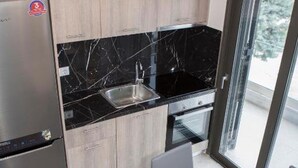 A modern kitchen with a built-in oven, a stainless steel refrigerator, and a black marble backsplash. - Sea View Frini- Lefkada (Lefkada)