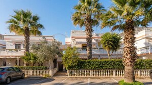 A residential area with palm trees, a car, and a building with balconies. - Apartment 'Casa Le Vele' with Private Terrace, Wi-Fi and Air Conditioning (Galatone)