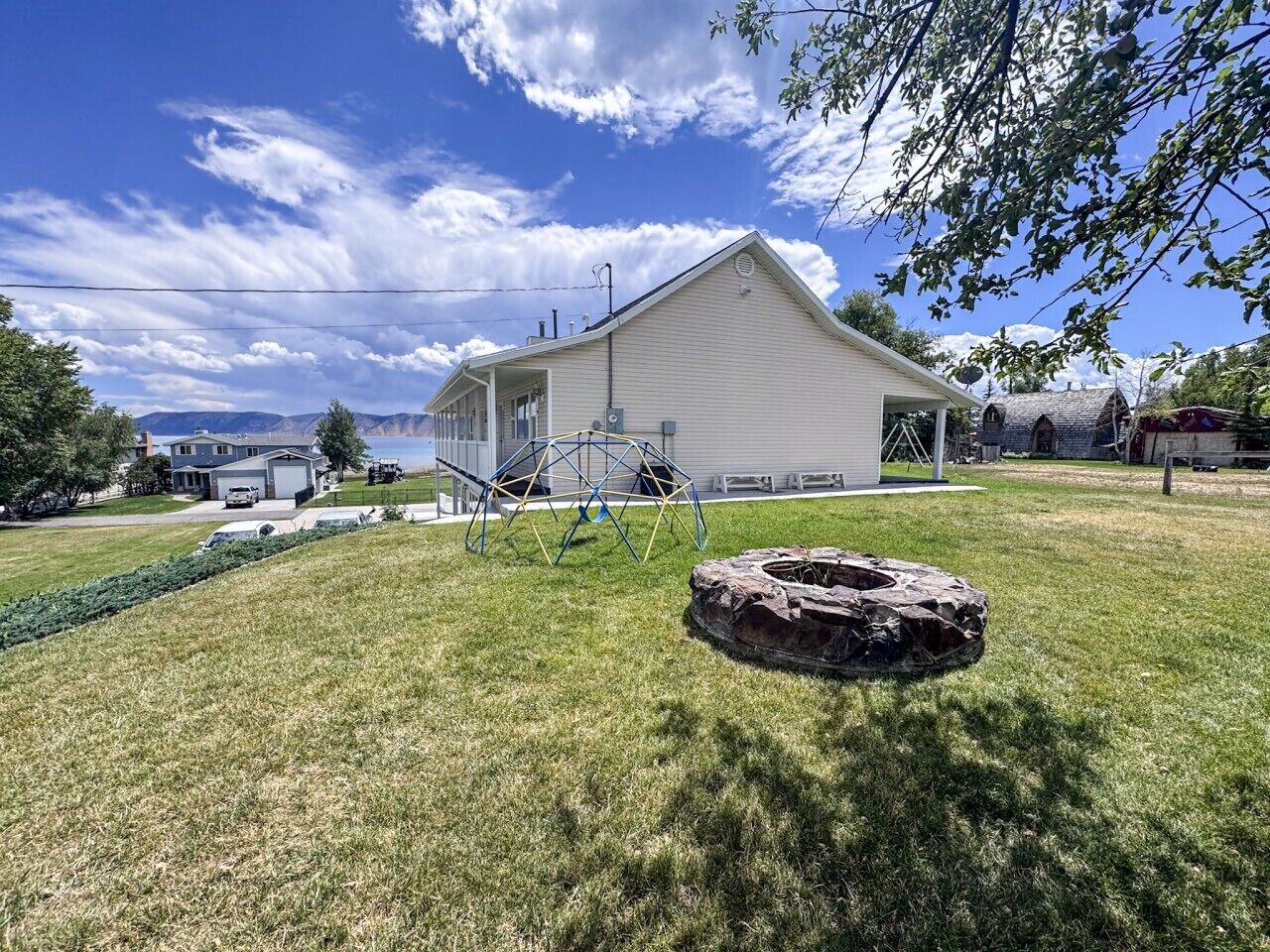 A house with a well-maintained lawn, a swing set, and a fire pit.