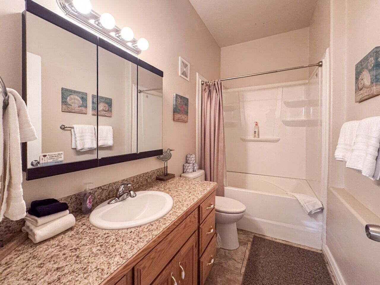 A bathroom with a sink, mirror, vanity, toilet, and shower.
